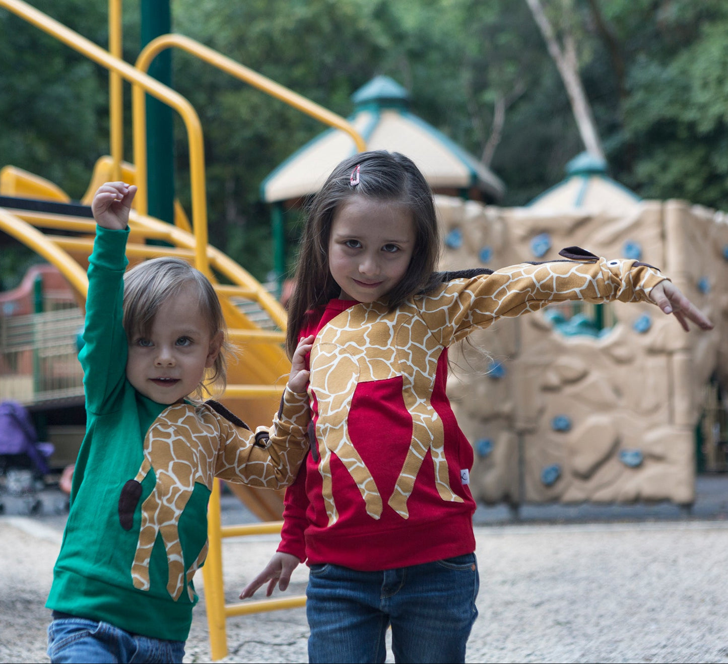Kinder mit Luanimals Giraffe Gerda in rot und grün auf dem Spielplatz