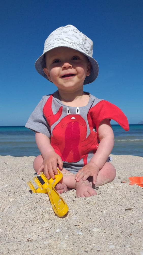 Fröhliches Kind spielt am Strand mit T-Shirt für Kinder mit Tiermotiv Krabbe Karli in grau und rot von Luanimals