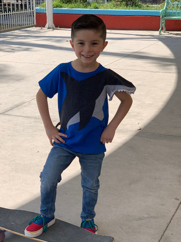 Ein Kind mit einem Skateboard mit dem Luanimals T-Shirt Hai Henry in blau